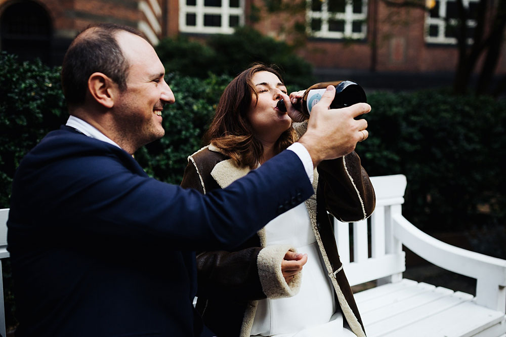 bride and groom drinking Champagne from a bottle at Copenhagen city Hall