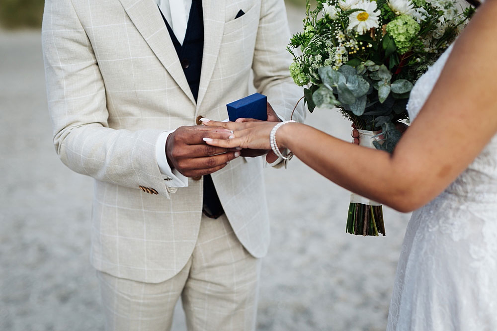 bride and groom exchanging rings in civil ceremony on the beach in Copenhagen