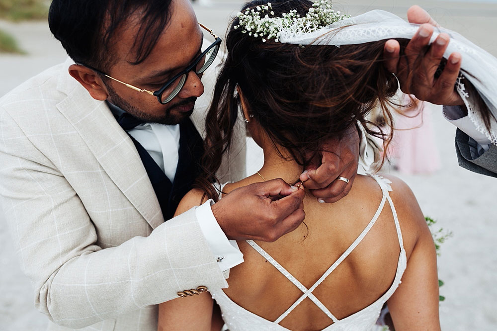 groom giving the bride a necklace at Amager Strand