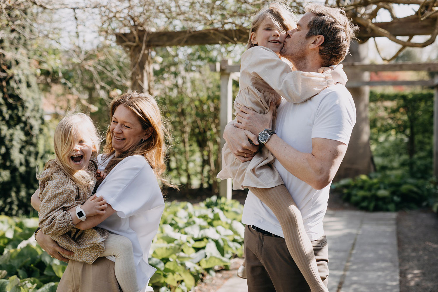 Family photo session in Copenhagen: A candid shot of a family sharing hugs and kisses in Frederiksberg Have