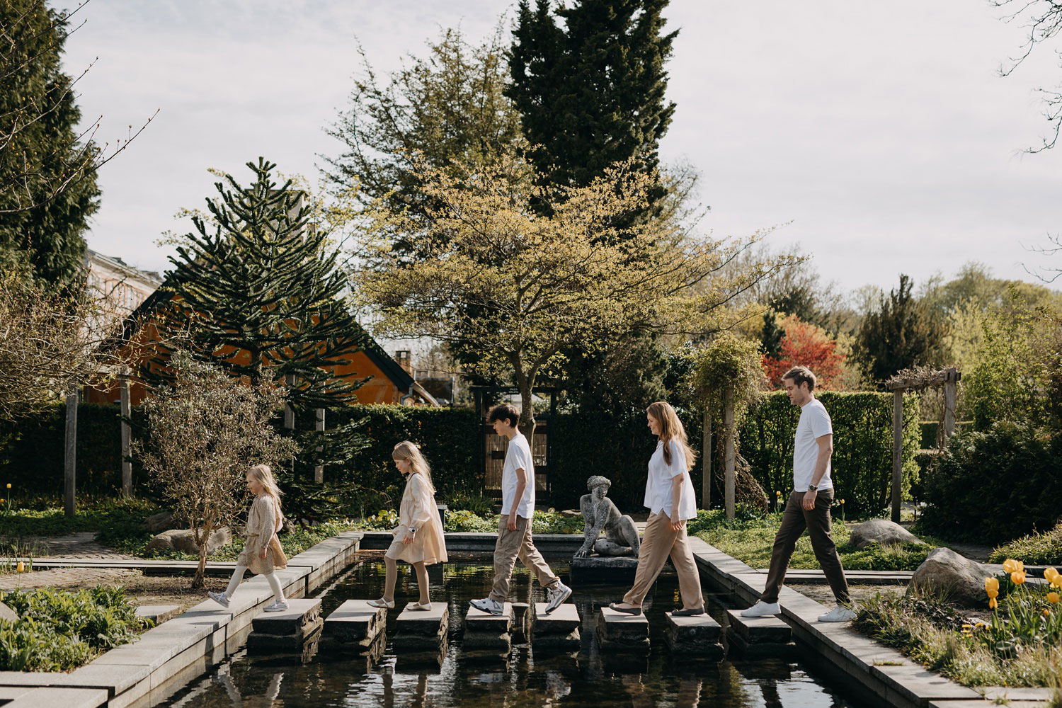 family photography in Copenhagen: family crossing a pond in Frederiksberg Have in Copenhagen