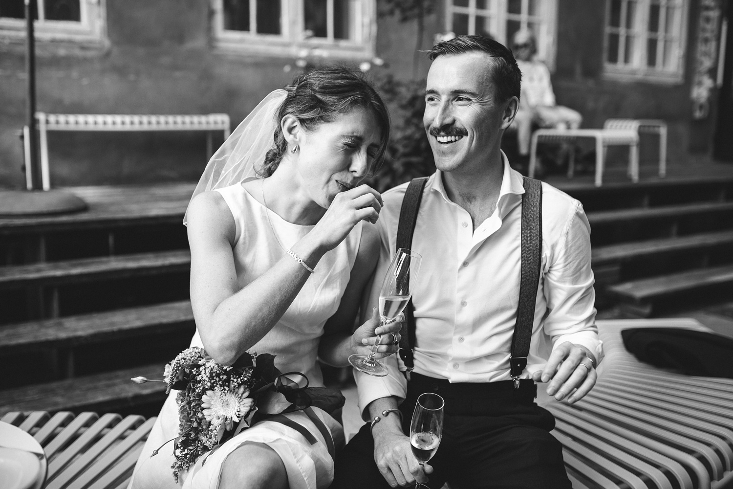 The bride and groom share a delicious Danish pastry at their intimate reception, smiling and savoring the sweet moment together.